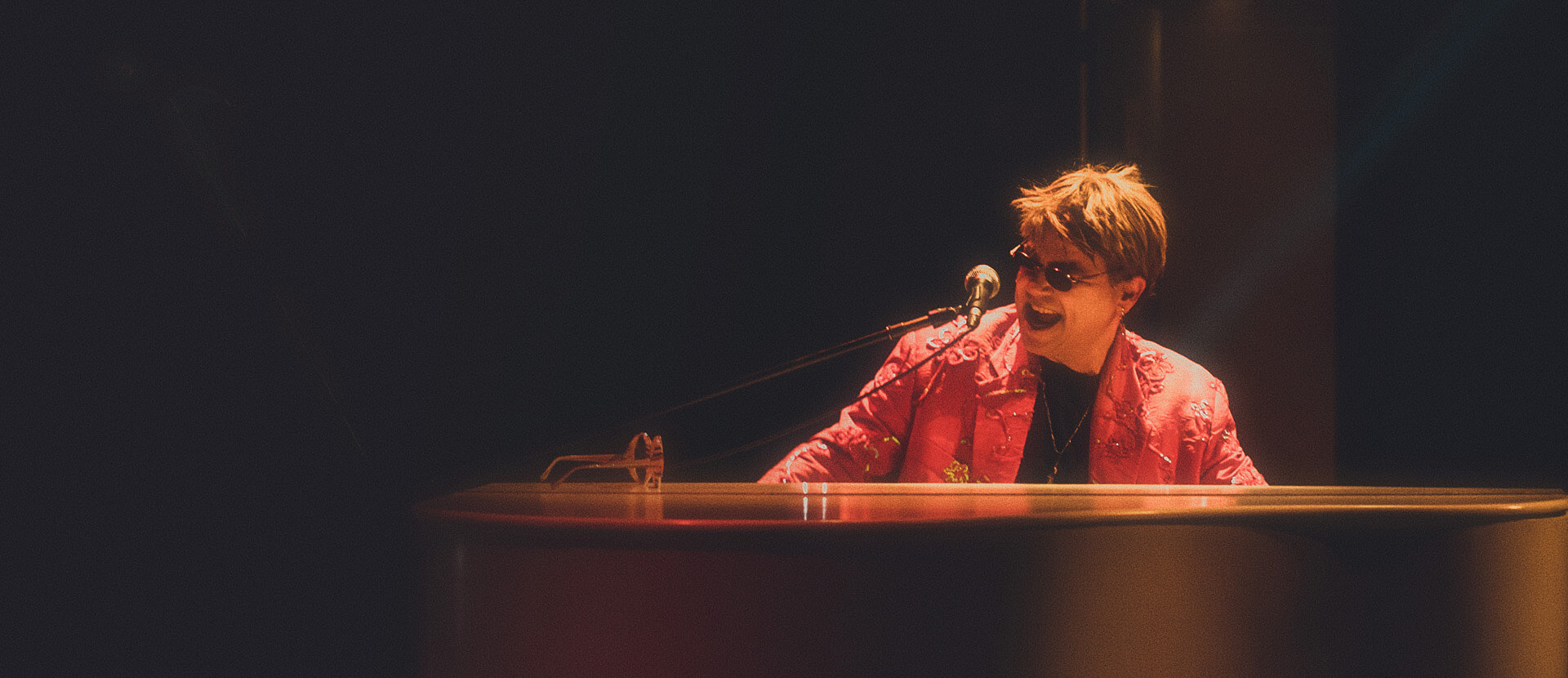 Maestro Rogério Martins caracterizado de Elton John tocando piano no show Your Song.