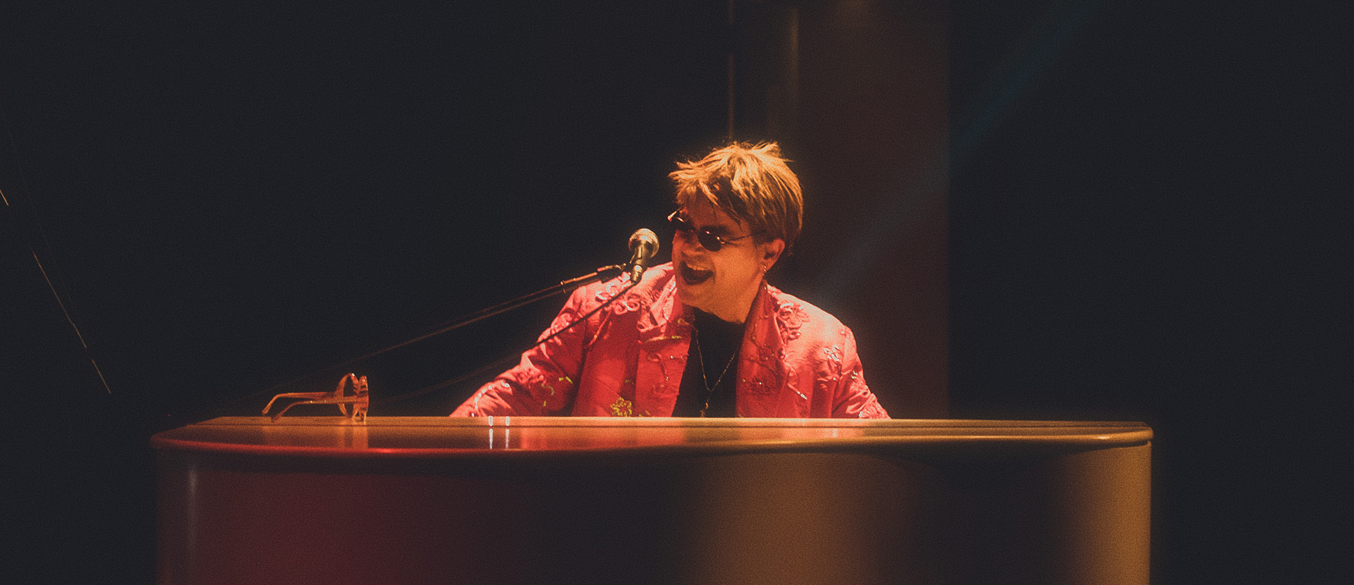 Maestro Rogério Martins caracterizado de Elton John tocando piano no show Your Song.