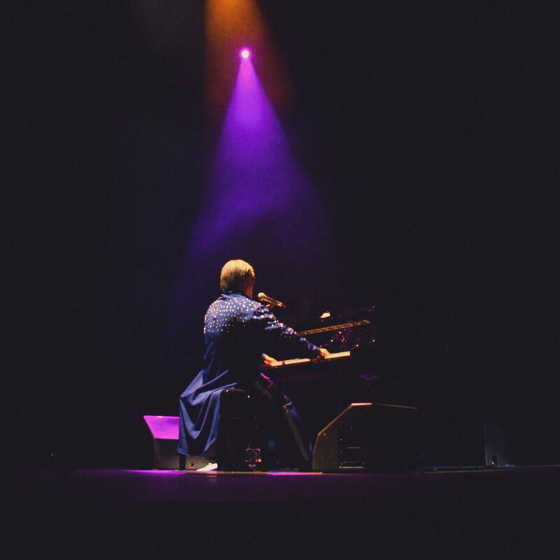 Maestro Rogério Martins caracterizado de Elton John no piano durante o show Your Song.