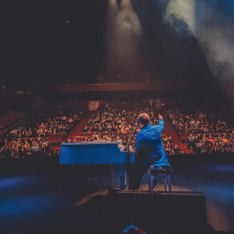 Maestro Rogério Martins em performance no show Your Song sob luz.